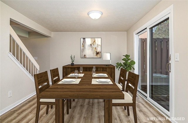 dining room with baseboards, stairs, a textured ceiling, and wood finished floors