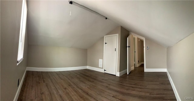 additional living space with baseboards, dark wood-style floors, and lofted ceiling