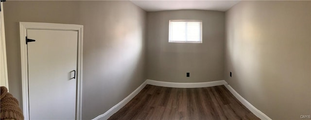 spare room with baseboards and wood finished floors