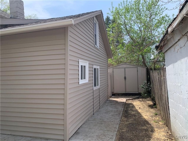 view of home's exterior featuring fence, an outdoor structure, and a storage unit