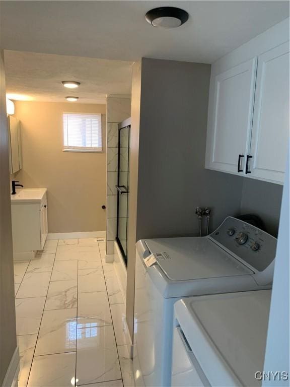 laundry room with laundry area, washing machine and clothes dryer, a sink, baseboards, and marble finish floor