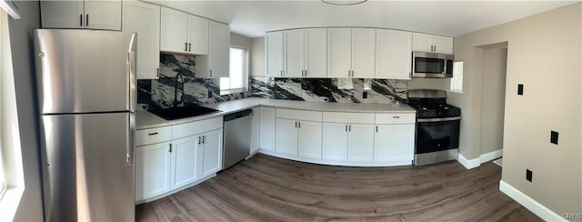 kitchen featuring white cabinets, stainless steel appliances, backsplash, and dark wood-type flooring
