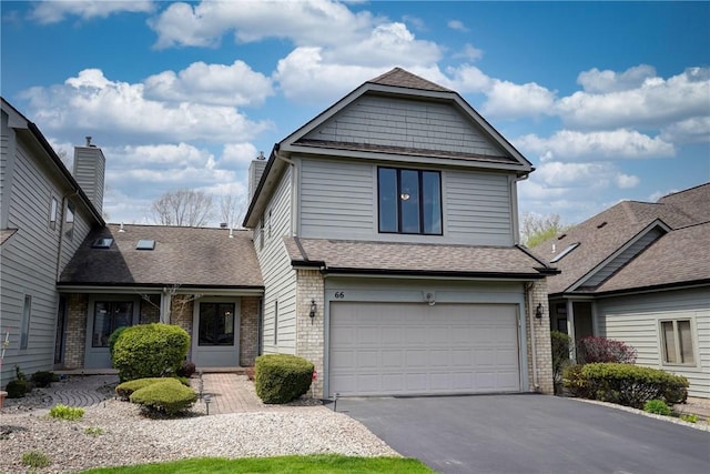 traditional home with brick siding, driveway, a shingled roof, and a garage