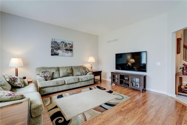 living area featuring baseboards, wood finished floors, and visible vents