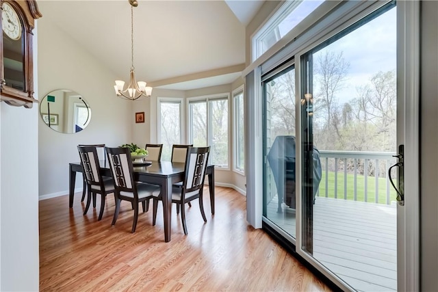 dining room featuring baseboards, light wood-style floors, a chandelier, and vaulted ceiling