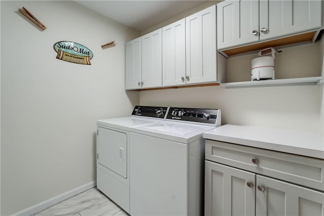 clothes washing area featuring baseboards, marble finish floor, cabinet space, and washer and dryer