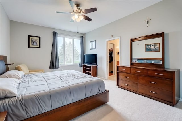 bedroom with baseboards, a ceiling fan, a spacious closet, and light carpet
