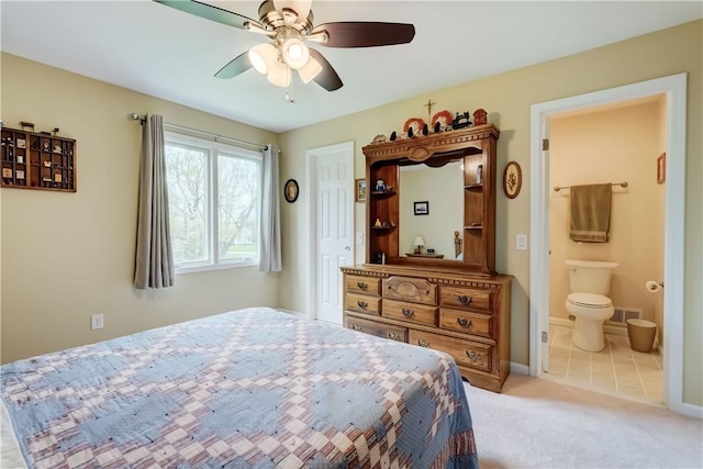 carpeted bedroom with a ceiling fan, baseboards, visible vents, and ensuite bath