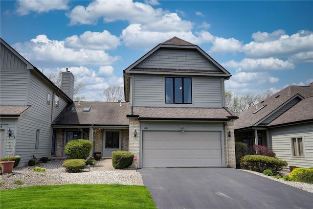 traditional-style house with brick siding, aphalt driveway, an attached garage, and roof with shingles