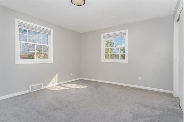carpeted empty room featuring baseboards and visible vents