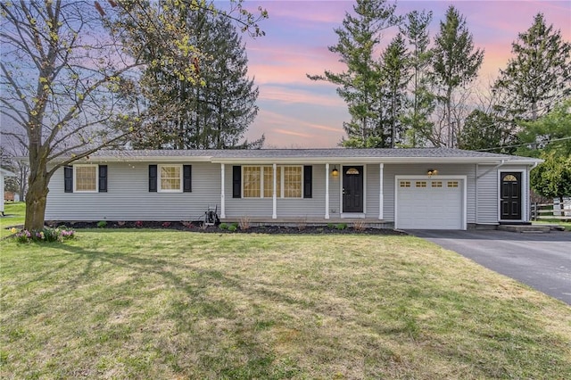 ranch-style home featuring a lawn, an attached garage, and aphalt driveway