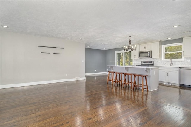 kitchen with a kitchen breakfast bar, appliances with stainless steel finishes, a center island, a notable chandelier, and open floor plan