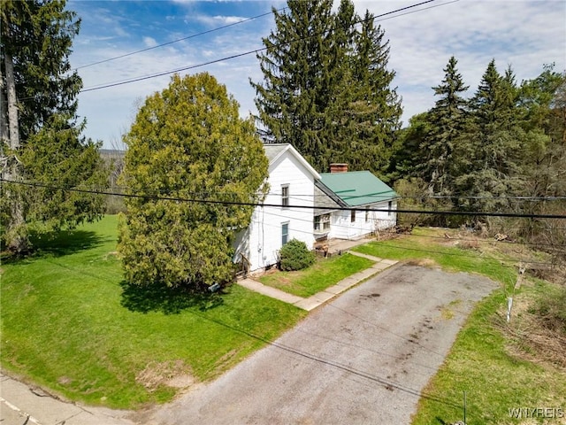 view of home's exterior featuring a lawn and dirt driveway