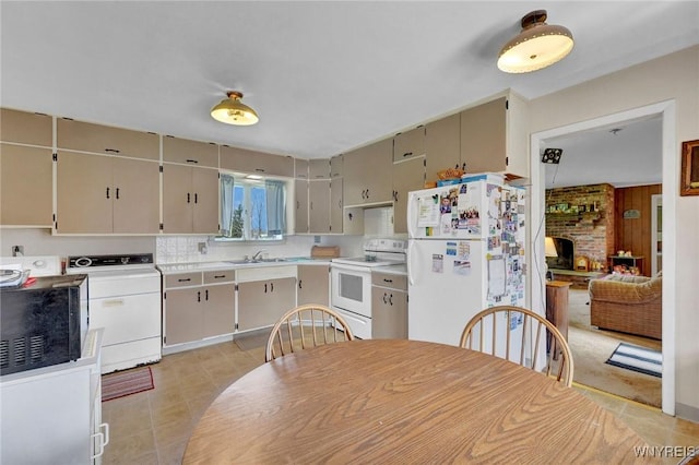 kitchen featuring white appliances, washer / clothes dryer, light countertops, a sink, and light tile patterned floors