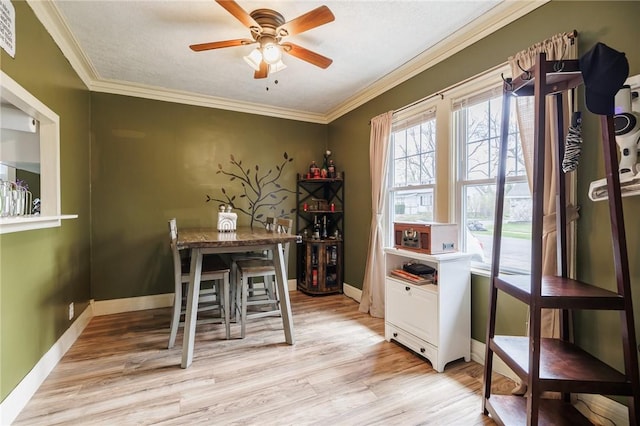 dining space featuring light wood-style floors, baseboards, crown molding, and a ceiling fan