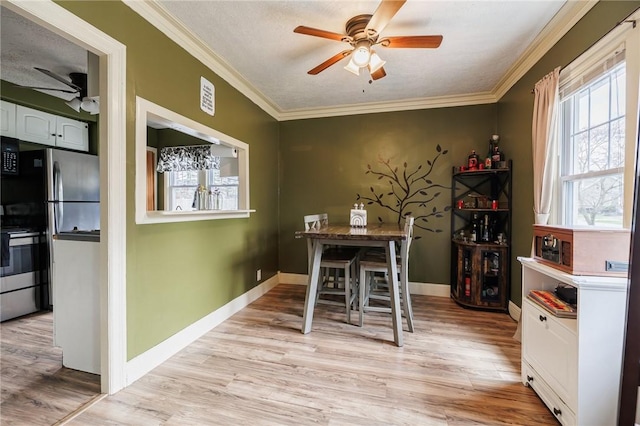 dining space with crown molding, a ceiling fan, and light wood-style flooring
