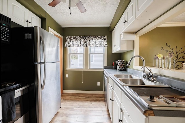 kitchen with ceiling fan, a sink, a textured ceiling, freestanding refrigerator, and white cabinetry