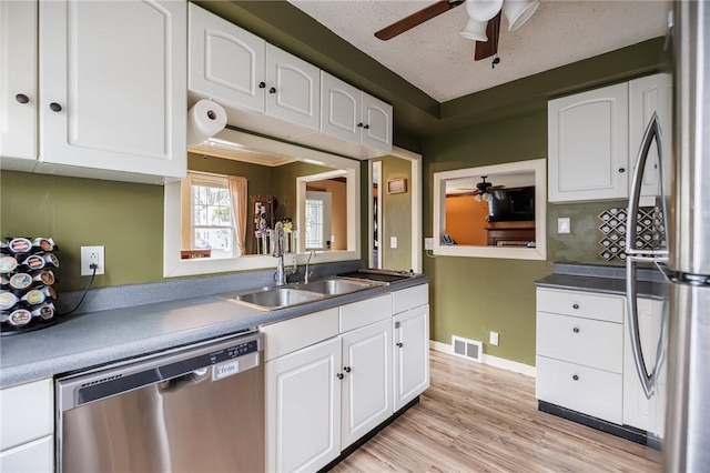 kitchen with a sink, appliances with stainless steel finishes, a ceiling fan, and white cabinetry