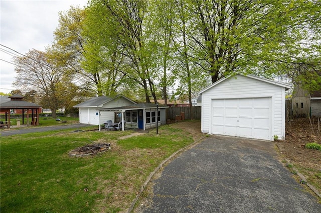 view of front facade with an outdoor structure, a garage, a front lawn, a gazebo, and driveway