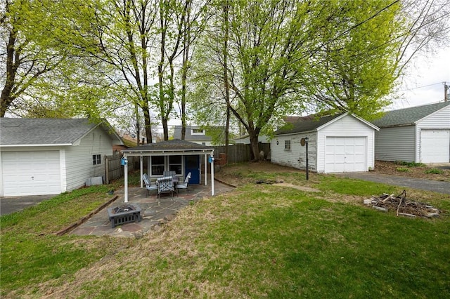 view of yard featuring fence, a fire pit, an outdoor structure, and a garage