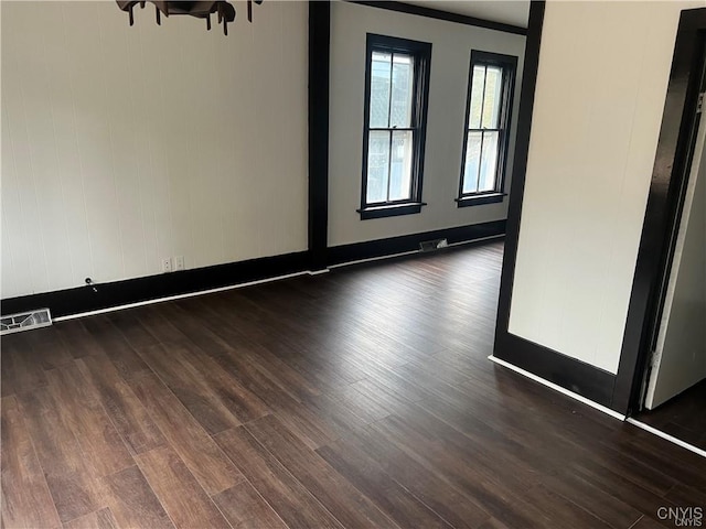unfurnished room with baseboards, visible vents, and dark wood-type flooring