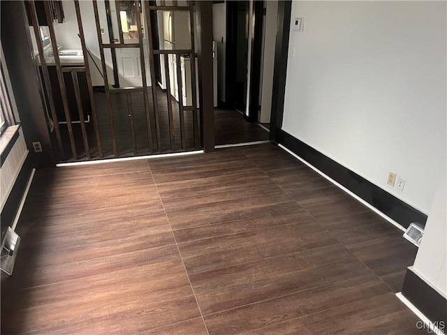 empty room with dark wood-type flooring, baseboards, and visible vents