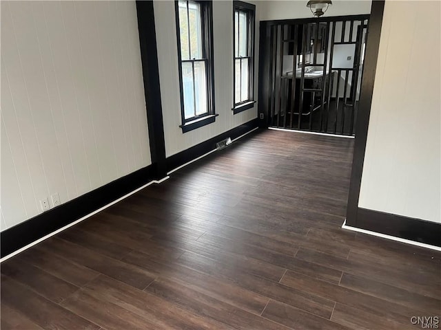unfurnished room with baseboards, visible vents, and wood finished floors