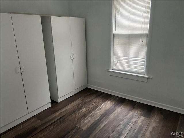 unfurnished bedroom with baseboards and dark wood finished floors
