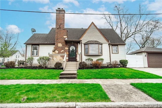 view of front of home with a detached garage, an outbuilding, a front yard, and a chimney