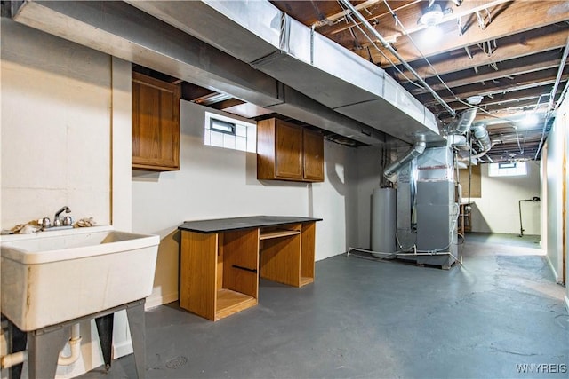 basement featuring heating unit, water heater, a sink, and a wealth of natural light