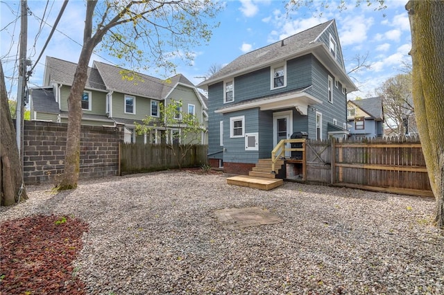 back of house with a shingled roof, fence, and a residential view
