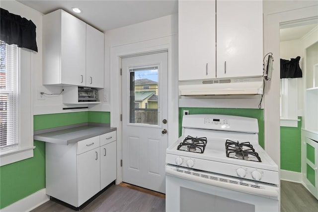 kitchen with light wood finished floors, under cabinet range hood, white range with gas cooktop, and white cabinetry