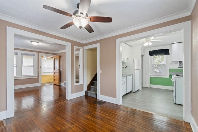 unfurnished living room with stairway, baseboards, a ceiling fan, and dark wood-style flooring