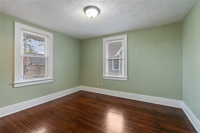 unfurnished room with a textured ceiling, baseboards, and wood finished floors
