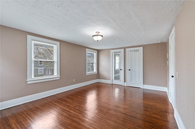 unfurnished room with baseboards, a textured ceiling, and wood finished floors