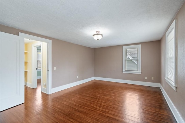 spare room featuring a textured ceiling, baseboards, and wood finished floors