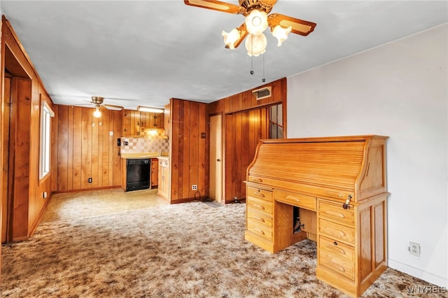 unfurnished office featuring a ceiling fan, wood walls, visible vents, and baseboards