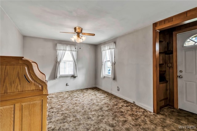 carpeted foyer entrance with a ceiling fan, baseboards, and plenty of natural light