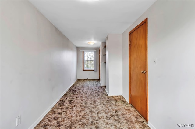 corridor with baseboards and light colored carpet