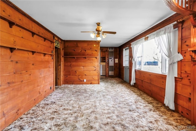 carpeted empty room featuring a ceiling fan and wooden walls