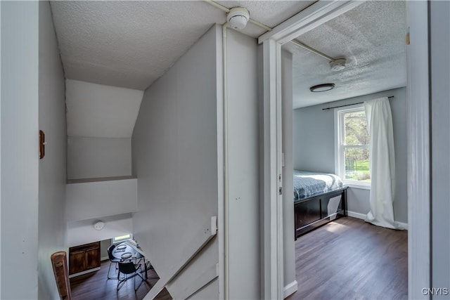 hall with baseboards, a textured ceiling, and wood finished floors