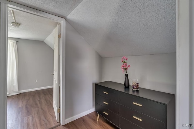 additional living space featuring baseboards, a textured ceiling, wood finished floors, and lofted ceiling