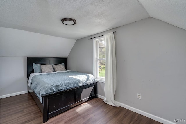 bedroom featuring baseboards, wood finished floors, a textured ceiling, and lofted ceiling