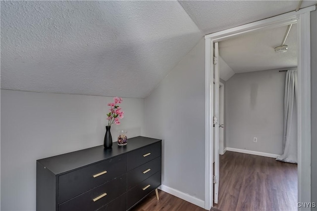 additional living space with baseboards, a textured ceiling, lofted ceiling, and dark wood-style floors