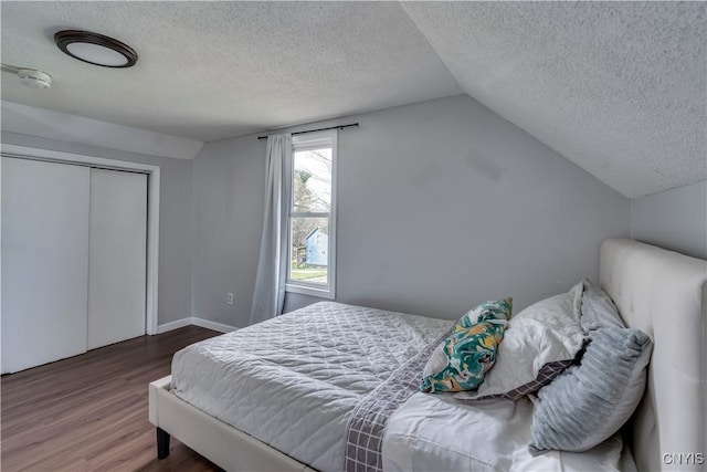 bedroom featuring a textured ceiling, vaulted ceiling, wood finished floors, and a closet
