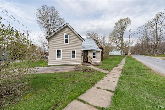view of front of home with metal roof and a front lawn