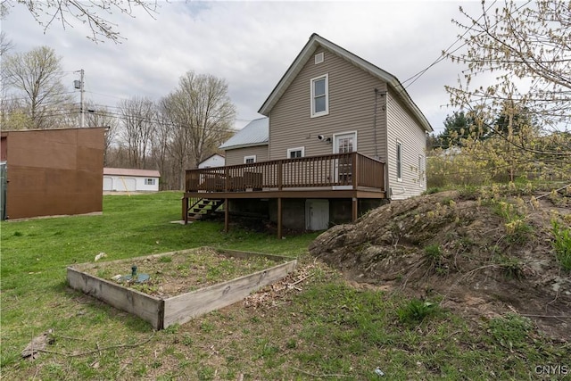 back of property featuring a lawn, a wooden deck, and a vegetable garden