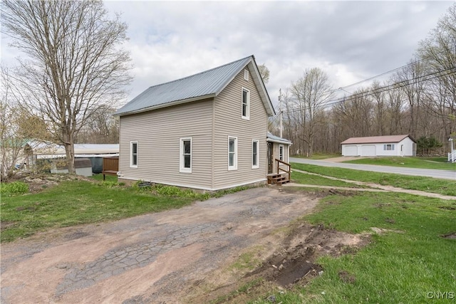 view of side of home with a garage, a yard, driveway, and metal roof