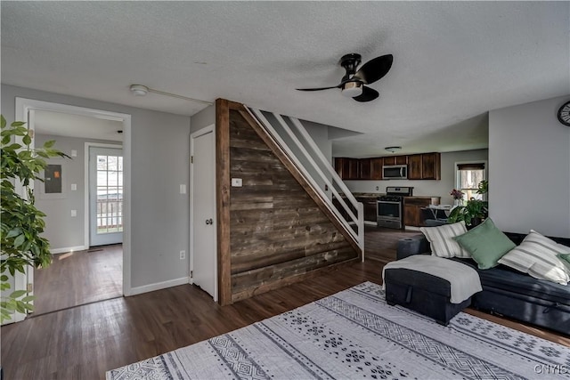 living area with a ceiling fan, wood finished floors, and stairway