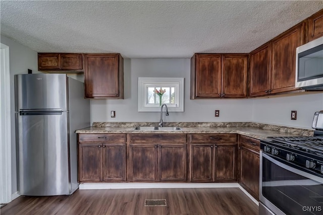 kitchen featuring a textured ceiling, visible vents, appliances with stainless steel finishes, dark wood finished floors, and a sink